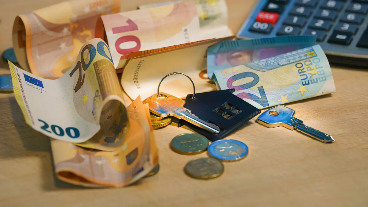 Personne consultant son avis de taxe foncière sur un ordinateur, avec calendrier et relevé bancaire à côté.